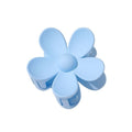 La pince à cheveux SOHO Bloom en bleu clair présente une finition lisse et un motif floral arrondi à cinq pétales, vu de dessus.