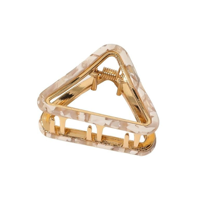 The SOHO Ea Hair Claw - Marble by SOHO is a triangular hair accessory featuring a marbled beige and gold design with metallic spring and prongs for secure grip, shown on a plain white background.