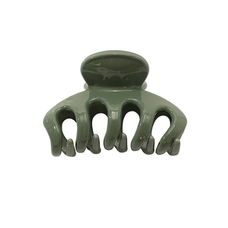 The SOHO Esta Hair Claw - Green by SOHO is a small green plastic clip with five wide, curved prongs and a rounded top handle for extra grip, shown against a white background.