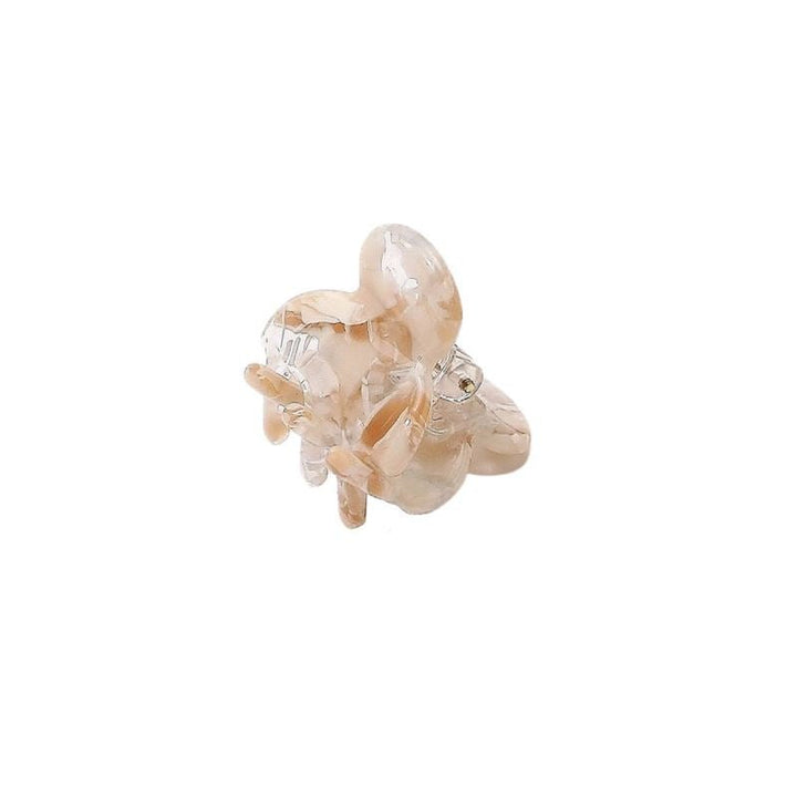 The SOHO Hara Mini Hair Claw in Clay by SOHO is a translucent beige resin ring with an abstract flower-like cluster of smooth, rounded petals, reminiscent of a mini hair claw, shown on a plain white background.