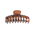 La pince à cheveux SOHO Kana Hair Claw - Tortoise est une grande pince en plastique marron de SOHO avec des dents incurvées et une charnière à ressort, offrant une forte adhérence pour tous les types de cheveux et maintenant vos cheveux en place.