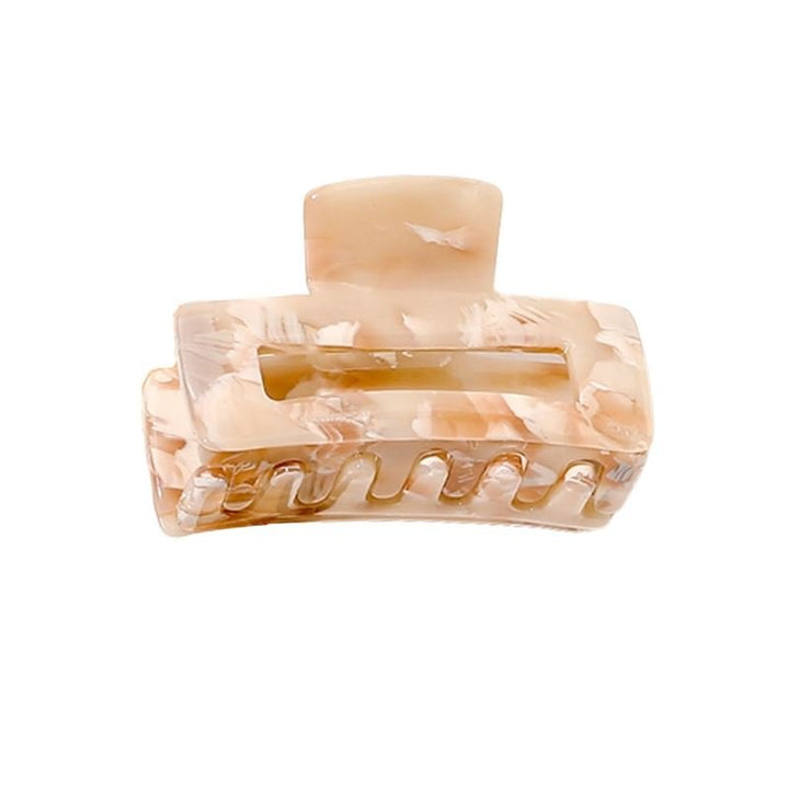 The SOHO Leia Mini Hair Claw in Beige Marble features a rectangular cutout and interlocking teeth, offering effortless hairstyling. This light beige marbled clip is shown against a white background.