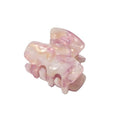 La mini-barrette SOHO Loa - Blush de SOHO présente un design marbré rose pâle, une finition brillante, des dents incurvées et une forme rectangulaire, parfaite comme petite barrette pour une élégance quotidienne.