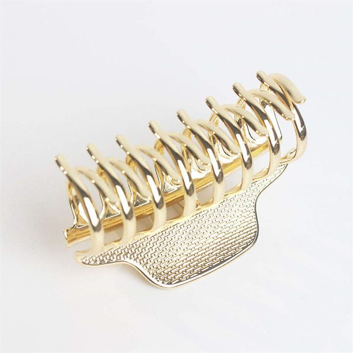The SOHO London Metal Hair Claw in gold by SOHO features interlocking prongs and a textured grip for secure, stylish hold. Shown against a plain white background, it’s both practical and elegant.